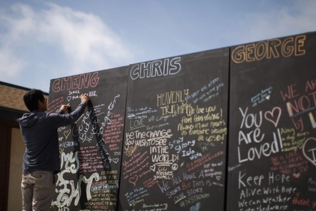 Un estudiante escribe mensajes de tiza en una pared en memoria de los estudiantes muertos en el Día de Duelo y reflexión para las víctimas de una matanza en la Universidad de California en Santa Bárbara / Davis  McNew/ AFP