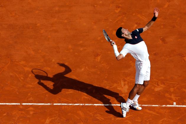 Djokovic serves to Federer during their semi-final match at the Monte Carlo Masters in Monaco