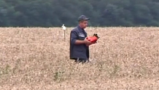 Still image from video shows a rescue worker carrying a flight data recorder at the crash site of Malaysia Airlines Flight MH17 in Hrabove