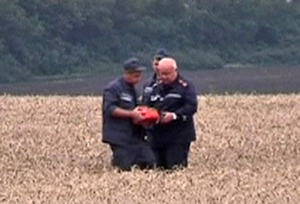 Still image from video shows a rescue worker showing a flight data recorder to a colleague at the crash site of Malaysia Airlines Flight MH17 in Hrabove