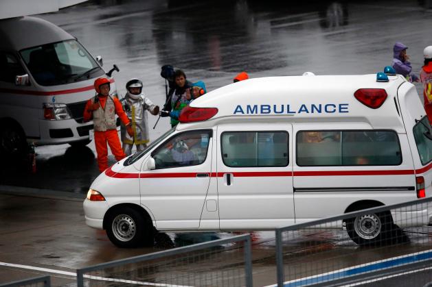 Marshalls clear the way for an ambulance after the race was stopped following a crash by Marussia Formula One driver Bianchi of France at the Japanese F1 Grand Prix at the Suzuka Circuit