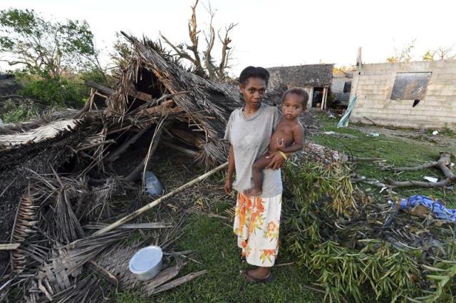  Lana Silona sostiene en brazos a su hijo Costello junto a las ruinas de su casa en la isla de Tanna en Vanuatu hoy, martes 17 de marzo de 2015. El paso del ciclón Pam ha causado al menos 11 muertos en Vanuatu, donde los equipos de rescate intentan evaluar los daños, mientras las autoridades temen que los supervivientes de las zonas más remotas se enfrenten pronto a una hambruna por la falta de provisiones. EFE/Dave Hunt 