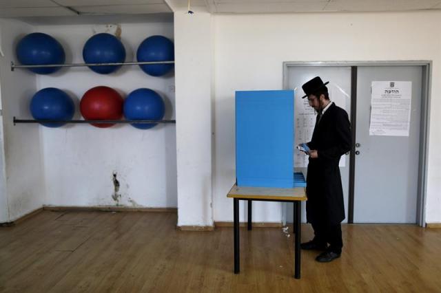  Un judío ultraortodoxo ejerce su derecho al voto en un colegio electoral durante la celebración de las elecciones generales en el asentamiento judío de Kiryat Arba cerca de la localidad palestina de Hebrón hoy, martes 17 de marzo de 2015. Casi 5,9 millones de ciudadanos israelíes podrán ejercer su derecho al voto hasta las 22.00 hora local (20.00 GMT), e inmediatamente después comenzarán a publicarse los primeros sondeos a pie de urna y se iniciará el recuento de votos, que se espera que concluya al amanecer del día siguiente. EFE/Abir Sultan