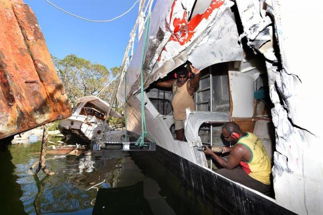 Dos hombres realiza reparaciones en un bote golpeado por otra embarcación durante el paso del ciclón Pam hoy, martes 17 de marzo de 2015, en Port Vila, Vanuatu. La cifra de fallecidos por el paso del poderoso ciclón Pam de categoría 5 que golpeó el fin de semana Vanuatu se elevó de 6 a 24, informó Naciones Unidas. "Hay 24 fallecidos confirmados, 11 de Tafea, 8 de Efate y 5 de (la isla de) Tanna", indicó en su último informe la Oficina para la Coordinación de Asuntos Humanitarios (OCAH). 