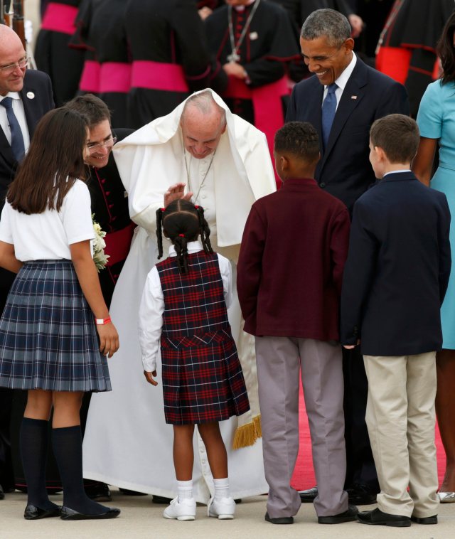 Pope Francis has part of his vestments get moved up to the back of his head by the wind as he greets children upon his arrival as he is welcomed by U.S. President Barack Obama (R) at Joint Base Andrews outside Washington September 22, 2015.  REUTERS/Kevin Lamarque (TPX IMAGES OF THE DAY)