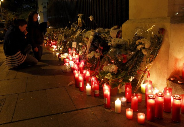 Two women pray in front of candles and flowers placed in tribute of victims following a series of deadly attacks in Paris outside French embassy in Madrid, Spain, November 14, 2015. REUTERS/Sergio Perez