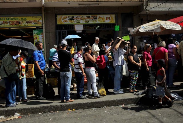 Alexandre (R), 7, sells plastic bags to citizens lining up to buy chicken at a store in Caracas, Venezuela December 8, 2015.  REUTERS/Nacho Doce