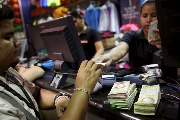 A man pays to the cashier, in Venezuelan bolivar notes, at a shopping center in Caracas, Venezuela, December 9, 2015.  REUTERS/Carlos Garcia Rawlins
