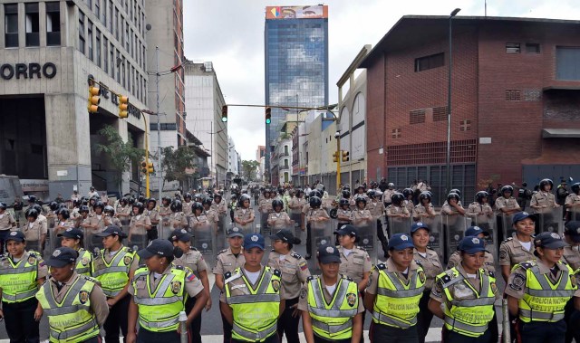 Venezuelan police officers, some in riot gear, line up in front of the the National Assembly in Caracas, on January 5, 2015. Venezuela's President Nicolas Maduro ordered the security forces to ensure the swearing-in of a new opposition-dominated legislature passes off peacefully Tuesday, after calls for rallies raised fears of unrest. AFP PHOTO/JUAN BARRETO / AFP / JUAN BARRETO