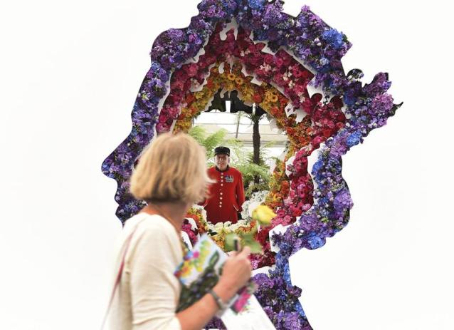 Una mujer pasa delante de la instalación floral con la silueta de la reina Isabell II de Inglaterra titilada "Detrás de cada gran florista", diseñada por Veevers Carter, durante la Exposición De Flores De Chelsea, en Londres, Reino Unido, hoy, 23 de mayo de 2016. EFE/Andy Rain