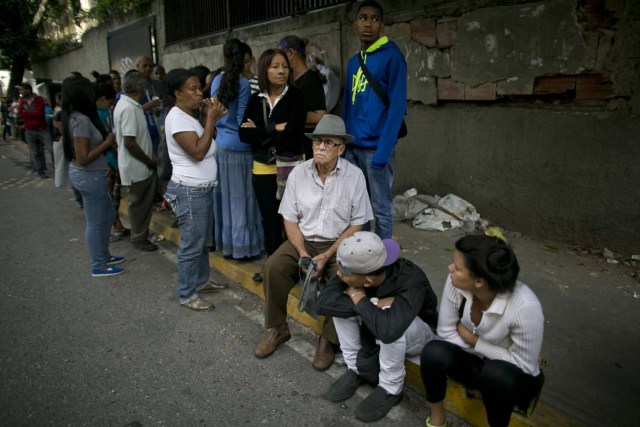 En esta imagen, tomada el 4 de julio de 2016, un grupo de personas espera en fila para comprar comida en el exterior de un supermercado en Caracas, Venezuela. La magnitud del derrumbe económico se puede medir en la longitud de las filas que aparecen en todos los barrios. (AP Foto/Ariana Cubillos)
