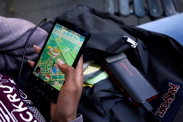 una mujer utiliza una batería para recargar su teléfono mientras juega "Pokémon Go" en Nueva York. Foto: REUTERS/Mark Kauzlarich