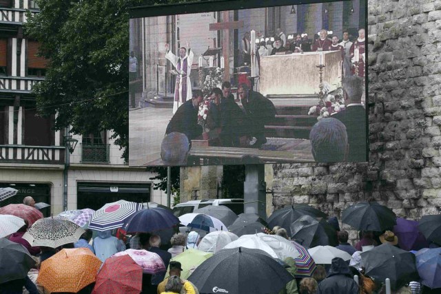 Mourners gather in the rain near a giant screen outside the Cathedral in Rouen, France, during a funeral service in memory of slain French parish priest Father Jacques Hamel at the Cathedral in Rouen, France, August 2, 2016.  Father Jacques Hamel was killed last week in an attack on a church at Saint-Etienne-du-Rouvray near Rouen that was carried out by assailants linked to Islamic State.   REUTERS/Jacky Naegelen