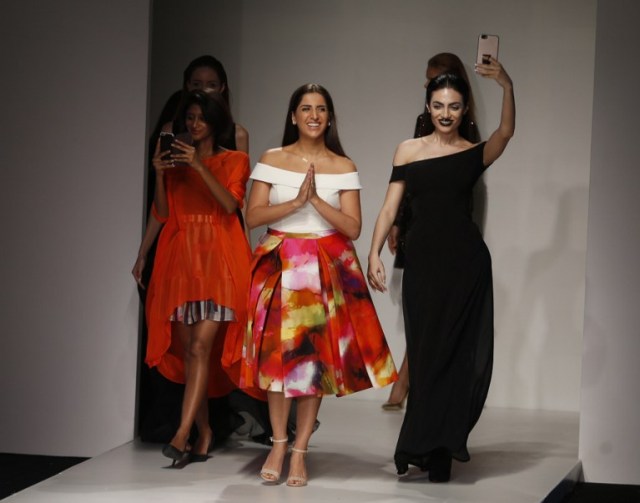 Lebanese designer Aiisha Ramadan (C) walks down the catwalk with Emirati model Rafeea Al-Hajsi (R) and other models wearing her designs the end of her show during the Arab Fashion Week in the United Arab Emirate of Dubai on October 9, 2016. Rafeea al-Hajsi fulfilled a dream by becoming the first Emirati model to strut the Arab Fashion Week catwalk after years battling social constraints. Hajsi's first appearance at a fashion show was earlier this year in France, when she modelled for Lebanese designer Ziad Nakad at Paris Fashion Week. / AFP PHOTO / KARIM SAHIB