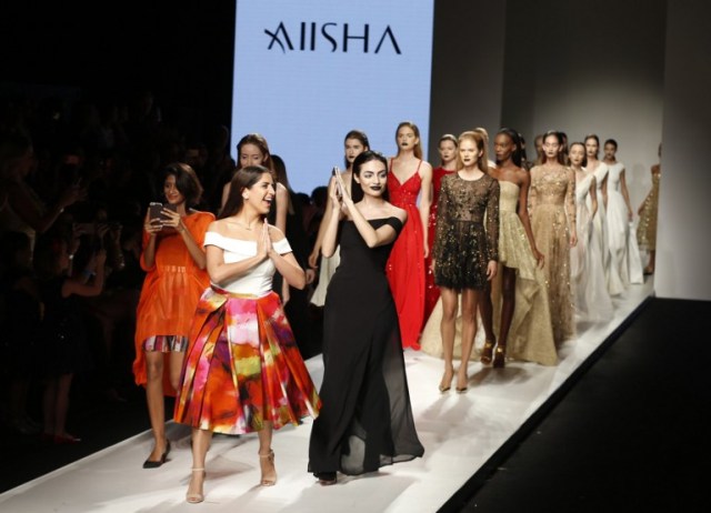 Lebanese designer Aiisha Ramadan (C) walks down the catwalk with Emirati model Rafeea Al-Hajsi (C-R) and other models wearing her designs the end of her show during the Arab Fashion Week in the United Arab Emirate of Dubai on October 9, 2016. Rafeea al-Hajsi fulfilled a dream by becoming the first Emirati model to strut the Arab Fashion Week catwalk after years battling social constraints. Hajsi's first appearance at a fashion show was earlier this year in France, when she modelled for Lebanese designer Ziad Nakad at Paris Fashion Week. / AFP PHOTO / KARIM SAHIB