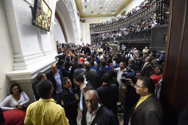 Members of the National Assembly react as supporters of Venezuelan President Nicolas Maduro force their way during an extraordinary session called by opposition leaders, in Caracas on October 23, 2016. The Democratic Unity Movement(MUD), opposite to Nicolas Maduro's government called a Parliamentary session to discuss restructuring of the Boliviarian Republic of Venezuela's Constitution, the constitutional order and democracy as main issues. Demonstrators outside the building forced their entrance to interrupt the debate and the session was suspended. / AFP PHOTO / JUAN BARRETO