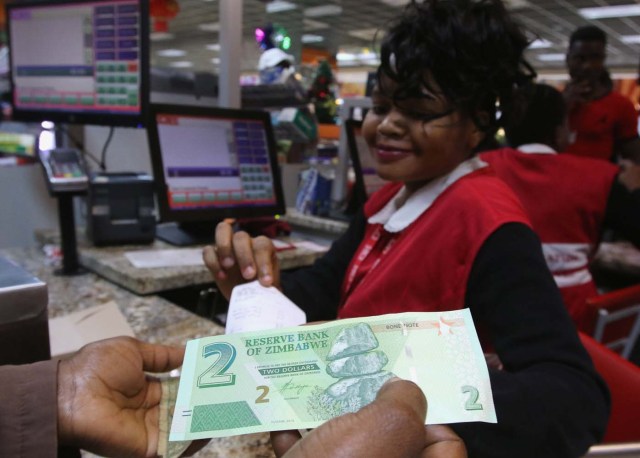 A till operator poses with new bond notes at a supermarket in the capital Harare,Zimbabwe, November 28,2016.REUTERS/Philimon Bulawayo
