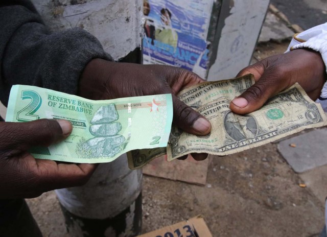 Illegal money changers pose while exchanging a new Zimbabwe bond note (L) and U.S. dollar notes in the capital Harare, Zimbabwe, November 28, 2016. REUTERS/Philimon Bulawayo