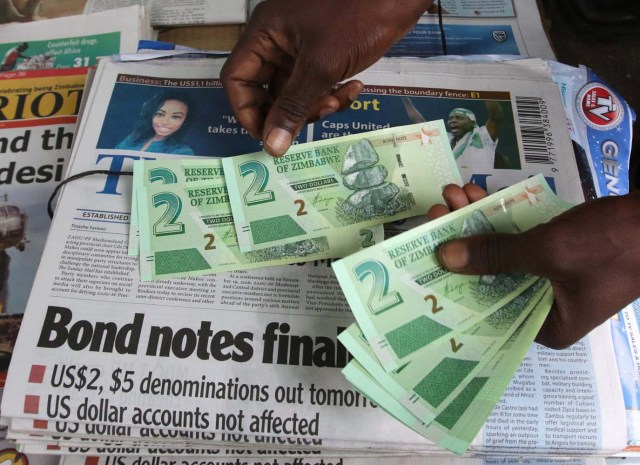 A street vendor poses with new bond notes in the capital Harare, Zimbabwe, November 28, 2016. REUTERS/Philimon Bulawayo