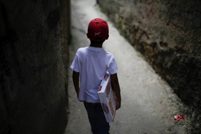 A boy walks with a toy received during toy distribution program with Miguel Pizarro, deputy of the Venezuelan coalition of opposition parties (MUD), in an alley at the slum of Petare in Caracas, Venezuela December 20, 2016. Picture taken December 20, 2016. REUTERS/Marco Bello