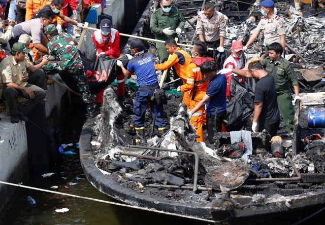 ATTENTION EDITORS - VISUAL COVERAGE OF SCENES OF INJURY OR DEATHPolice, Red Cross and rescue workers remove the remains of victims after a fire ripped through a boat carrying tourists to islands north of the capital, at Muara Angke port in Jakarta, Indonesia January 1, 2017. REUTERS/Darren Whiteside