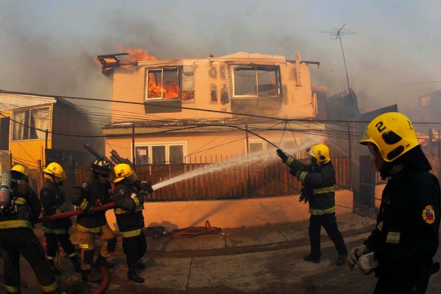 CH01. VALPARAISO (CHILE), 02/01/2017.- Personal de bomberos combate un incendio forestal en el sector de Playa Ancha en la ciudad de Valparaíso (Chile) hoy, 2 de enero de 2016, que afectó a viviendas y vecinos del sector. Un incendio forestal que estalló hoy en la parte alta del puerto chileno de Valparaíso llevó a las autoridades a declarar alerta roja en la ciudad y a disponer la evacuación preventiva de unas 25 viviendas próximas al foco de fuego, informaron fuentes oficiales. EFE/SEBASTIAN CISTERNAS