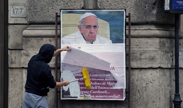 A worker covers with a banner reading "illegal poster" a poster depicting Pope Francis and accusing him of attacking conservative Catholics is seen in Rome, Italy, February 5, 2017. REUTERS/Max Rossi