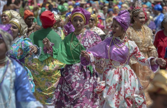 Women dressed as "madamas" dance as they take part in a parade during the Carnival in El Callao, Bolivar state, Venezuela on February 26, 2017.  El Callao's carnival was recently named Unesco's Intangible Cultural Heritage of Humanity and is led by the madamas, the pillars of Callaoense identity representing Antillean matrons considered the communicators of values, who dance and wear colourful dresses. / AFP PHOTO / JUAN BARRETO