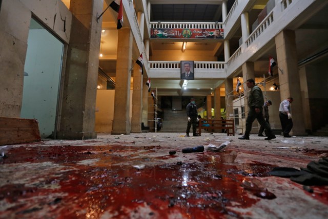 Syrian security forces inspect the scene of a reported suicide bombing at the old palace of justice building in Damascus on March 15, 2017. Two suicide bombings hit Damascus including the attack at the central courthouse that left at least 32 dead, as Syria's war entered its seventh year with the regime now claiming the upper hand. / AFP PHOTO / Louai Beshara