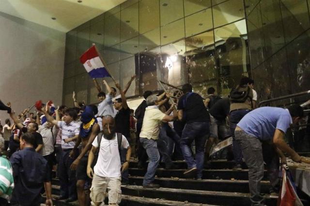 Manifestantes atacan hoy, viernes 31 de marzo de 2017, la sede del Congreso Nacional en Asunción (Paraguay). EFE