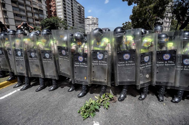 Riot police officers block an avenue during a protest against Nicolas Maduro's government in Caracas on April 4, 2017. Protesters clashed with police in Venezuela Tuesday as the opposition mobilized against moves to tighten President Nicolas Maduro's grip on power. Protesters hurled stones at riot police who fired tear gas as they blocked the demonstrators from advancing through central Caracas, where pro-government activists were also planning to march. / AFP PHOTO / JUAN BARRETO