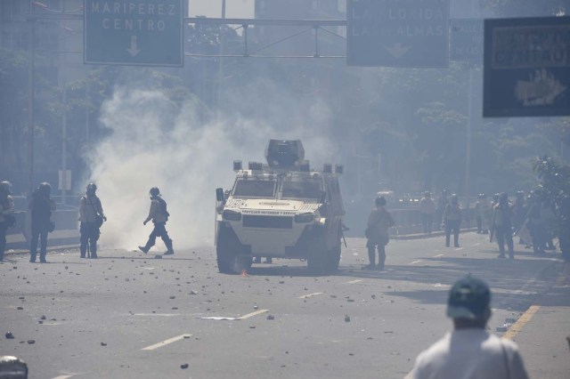 Riot police and demonstrators protesting against President Nicolas Maduro's government clash in Caracas on April 8, 2017. The opposition is accusing pro-Maduro Supreme Court judges of attempting an internal "coup d'etat" for attempting to take over the opposition-majority legislature's powers last week. The socialist president's supporters held counter-demonstrations on Thursday, condemning Maduro's opponents as "imperialists" plotting with the United States to oust him. / AFP PHOTO / JUAN BARRETO