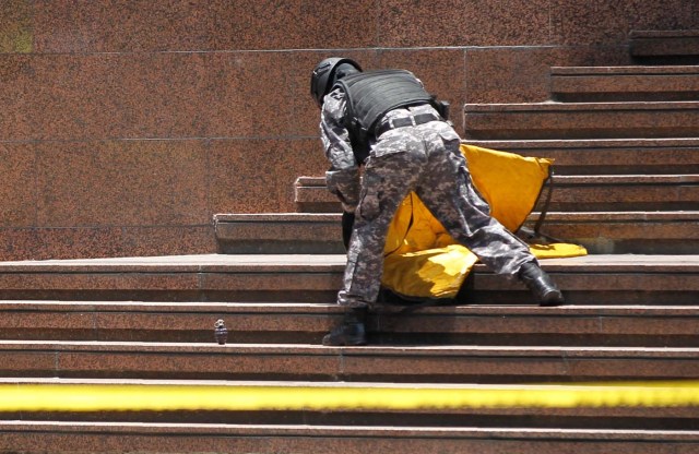 A security forces guard removes a grenade at a building entrance near the venue of a rally against Venezuela's President Nicolas Maduro in Caracas, Venezuela April 26, 2017. REUTERS/Christian Veron