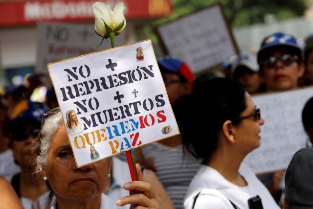 A woman holds up a placard that reads "No more repression. No more dead. We want peace" during a women's march to protest against President Nicolas Maduro's government in Caracas, Venezuela May 6, 2017. REUTERS/Carlos Garcia Rawlins