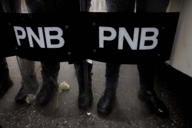 Flowers are seen next to the boots of the riot policemen during a women's march to protest against President Nicolas Maduro's government in Caracas, Venezuela May 6, 2017. REUTERS/Carlos Garcia Rawlins