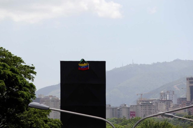 An opposition supporter hangs a national flag on top of an advertising structure while rallying against President Nicolas Maduro in Caracas, Venezuela, May 20, 2017. REUTERS/Christian Veron