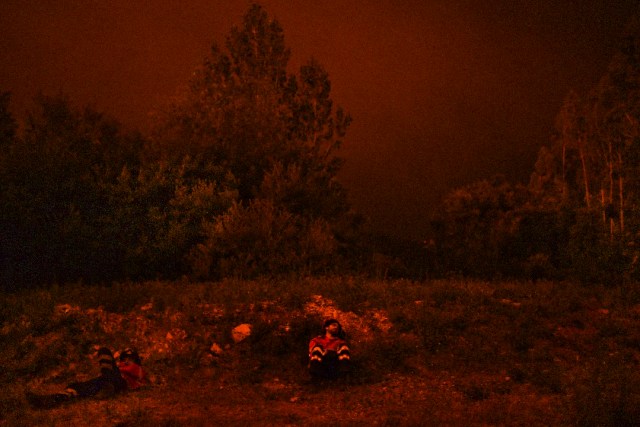 Firefighters rest during a wildfire at Penela, Coimbra, central Portugal, on June 18, 2017. A wildfire in central Portugal killed at least 25 people and injured 16 others, most of them burning to death in their cars, the government said on June 18, 2017. Several hundred firefighters and 160 vehicles were dispatched late on June 17 to tackle the blaze, which broke out in the afternoon in the municipality of Pedrogao Grande before spreading fast across several fronts. / AFP PHOTO / PATRICIA DE MELO MOREIRA