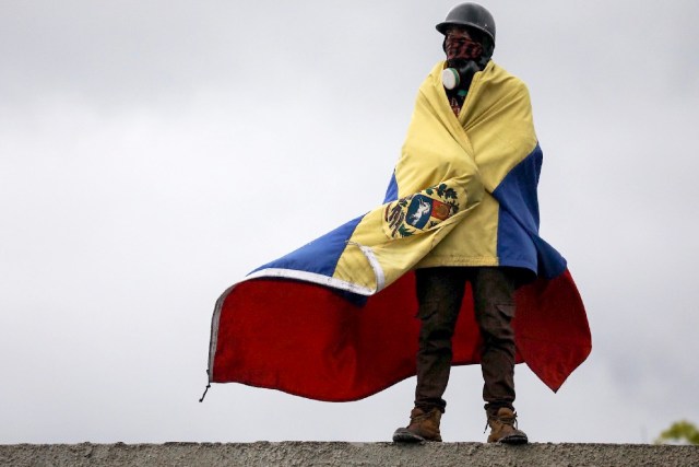 -FOTODELDIA- CAR23. CARACAS (VENEZUELA), 24/06/2017.- Un hombre que usa máscara de gas envuelve su cuerpo con una bandera venezolana durante una manifestación denominada "Venezuela le da un mensaje a la FAN (Fuerza Armada)" hoy, sábado 24 de junio de 2017, en Caracas (Venezuela). La oposición venezolana se moviliza hoy hasta las bases militares en Caracas y varios estados del país, mientras el chavismo marcha para conmemorar los 196 años de la Batalla de Carabobo, una acción militar decisiva en la independencia del país caribeño, y por el Día del Ejército Bolivariano. EFE/Miguel Gutiérrez