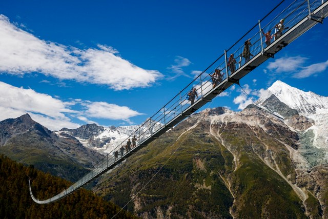 People walk on the "Europabruecke",  that is supposed to be the world's longest pedestrian suspension bridge with a length of 494m, after the official inauguration of the construction in Randa, Switzerland, on Saturday, July 29, 2017. The bridge is situated on the Europaweg that connects the villages of Zermatt and Graechen. (Valentin Flauraud/Keystone via AP)