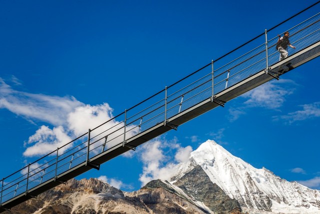 A person walks on the "Europabruecke",  supposed to be the world's longest pedestrian suspension bridge with a length of 494m, after the official inauguration of the construction in Randa, Switzerland, on Saturday, July 29, 2017. The bridge is situated on the Europaweg that connects the villages of Zermatt and Graechen. (Valentin Flauraud/Keystone via AP)