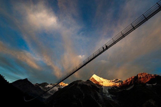A couple walks on the "Europabruecke",  supposed to be the world's longest pedestrian suspension bridge with a length of 494m, prior to the official inauguration of the construction in Randa, Switzerland, on Saturday, July 29, 2017. The bridge is situated on the Europaweg that connects the villages of Zermatt and Graechen. (Valentin Flauraud/Keystone via AP)