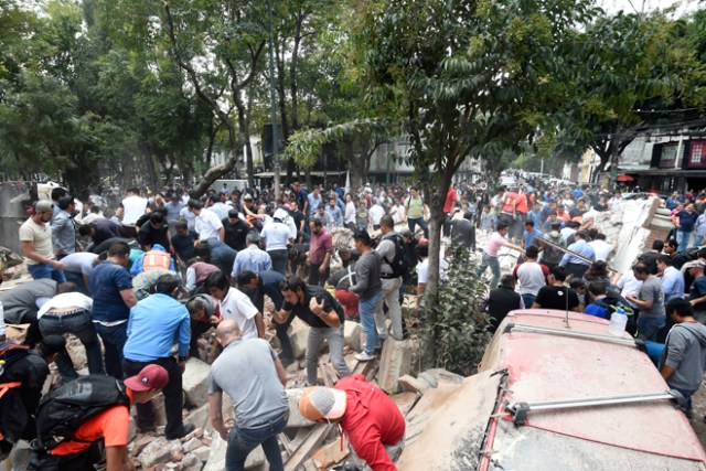 People remove debris of a building which collapsed after a quake rattled Mexico City on September 19, 2017. A powerful earthquake shook Mexico City on Tuesday, causing panic among the megalopolis' 20 million inhabitants on the 32nd anniversary of a devastating 1985 quake. The US Geological Survey put the quake's magnitude at 7.1 while Mexico's Seismological Institute said it measured 6.8 on its scale. The institute said the quake's epicenter was seven kilometers west of Chiautla de Tapia, in the neighboring state of Puebla. / AFP PHOTO / Alfredo ESTRELLA