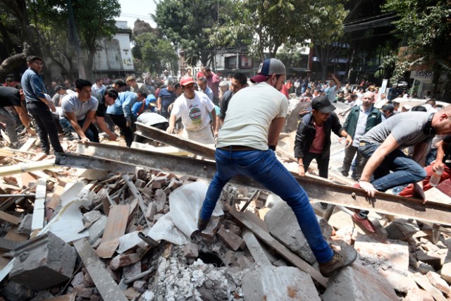 People remove debris of a building which collapsed after a quake rattled Mexico City on September 19, 2017. A powerful earthquake shook Mexico City on Tuesday, causing panic among the megalopolis' 20 million inhabitants on the 32nd anniversary of a devastating 1985 quake. The US Geological Survey put the quake's magnitude at 7.1 while Mexico's Seismological Institute said it measured 6.8 on its scale. The institute said the quake's epicenter was seven kilometers west of Chiautla de Tapia, in the neighboring state of Puebla. / AFP PHOTO / Alfredo ESTRELLA