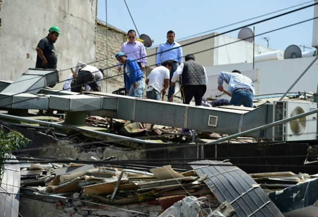 People look through debris of a building which collapsed when quake rattled Mexico City on September 19, 2017. A powerful earthquake shook Mexico City on Tuesday, causing panic among the megalopolis' 20 million inhabitants on the 32nd anniversary of a devastating 1985 quake. The US Geological Survey put the quake's magnitude at 7.1 while Mexico's Seismological Institute said it measured 6.8 on its scale. The institute said the quake's epicenter was seven kilometers west of Chiautla de Tapia, in the neighboring state of Puebla. / AFP PHOTO / Ronaldo SCHEMIDT