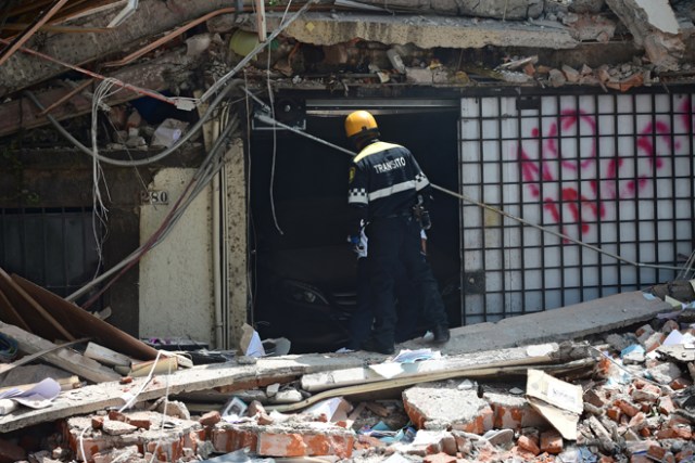 A traffic controller looks for possible victims inside the garage of a building which collapsed during a quake in Mexico City on September 19, 2017. A powerful earthquake shook Mexico City on Tuesday, causing panic among the megalopolis' 20 million inhabitants on the 32nd anniversary of a devastating 1985 quake. The US Geological Survey put the quake's magnitude at 7.1 while Mexico's Seismological Institute said it measured 6.8 on its scale. The institute said the quake's epicenter was seven kilometers west of Chiautla de Tapia, in the neighboring state of Puebla. / AFP PHOTO / Ronaldo SCHEMIDT