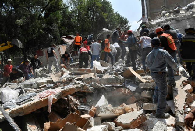 People remove debris of a building which collapsed after a quake rattled Mexico City on September 19, 2017. A powerful earthquake shook Mexico City on Tuesday, causing panic among the megalopolis' 20 million inhabitants on the 32nd anniversary of a devastating 1985 quake. The US Geological Survey put the quake's magnitude at 7.1 while Mexico's Seismological Institute said it measured 6.8 on its scale. The institute said the quake's epicenter was seven kilometers west of Chiautla de Tapia, in the neighboring state of Puebla. / AFP PHOTO / Omar TORRES