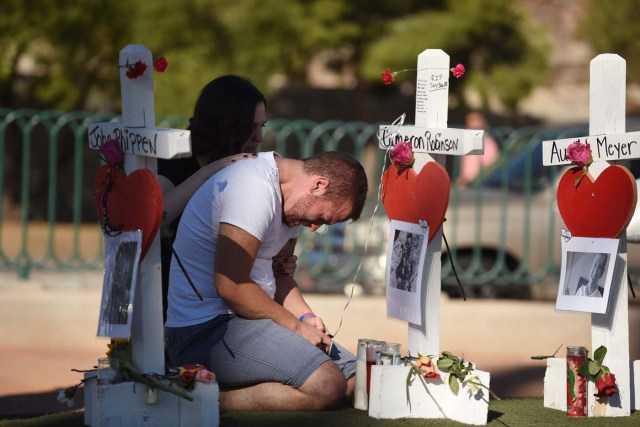 Ethan Avanzino grieves beside a white cross for his friend Cameron Robinson, one of 58 victims of Sunday night's mass shooting, on the Las Vegas Strip just south of the Mandalay Bay hotel, October 6, 2017 in Las Vegas, Nevada. On October 1, 2017 Stephen Paddock killed at least 58 people and injured more than 450 after he opened fire on a large crowd at the Route 91 Harvest country music festival. The massacre is one of the deadliest mass shooting events in US history. / AFP PHOTO / Robyn Beck