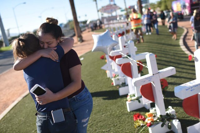Melissa Gerber (L) and Sandra Serralde (R) comfort each other beside 58 white crosses for the victims of Sunday night's mass shooting on the south end of the Las Vegas Strip, October 6, 2017 in Las Vegas, Nevada. On October 1, 2017 Stephen Paddock killed at least 58 people and injured more than 450 after he opened fire on a large crowd at the Route 91 Harvest country music festival. The massacre is one of the deadliest mass shooting events in US history. / AFP PHOTO / Robyn Beck