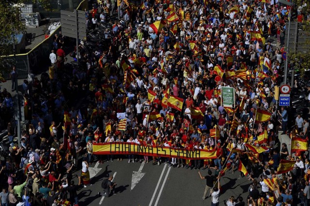 Protesters hold a giant Spanish flag reading "Catalonia is Spain" during a demonstration called by "Societat Civil Catalana" (Catalan Civil Society) to support the unity of Spain on October 8, 2017 in Barcelona. Spain braced for more protests despite tentative signs that the sides may be seeking to defuse the crisis after Madrid offered a first apology to Catalans injured by police during their outlawed independence vote. / AFP PHOTO / LLUIS GENE