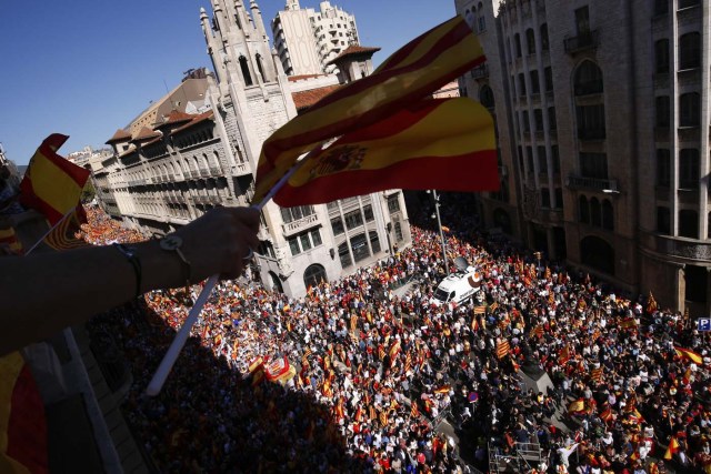 Protesters hold Spanish flags from a balcony during a demonstration called by "Societat Civil Catalana" (Catalan Civil Society) to support the unity of Spain on October 8, 2017 in Barcelona. Spain braced for more protests despite tentative signs that the sides may be seeking to defuse the crisis after Madrid offered a first apology to Catalans injured by police during their outlawed independence vote. / AFP PHOTO / PAU BARRENA